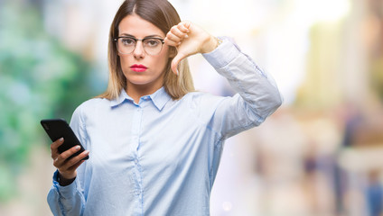 Young beautiful business woman texting message using smartphone over isolated background with angry face, negative sign showing dislike with thumbs down, rejection concept