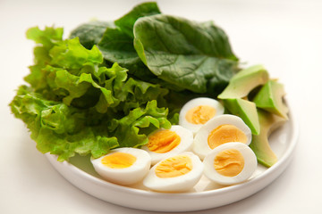 light breakfast: boiled quail eggs, spinach, lettuce, avocado. On a white plate