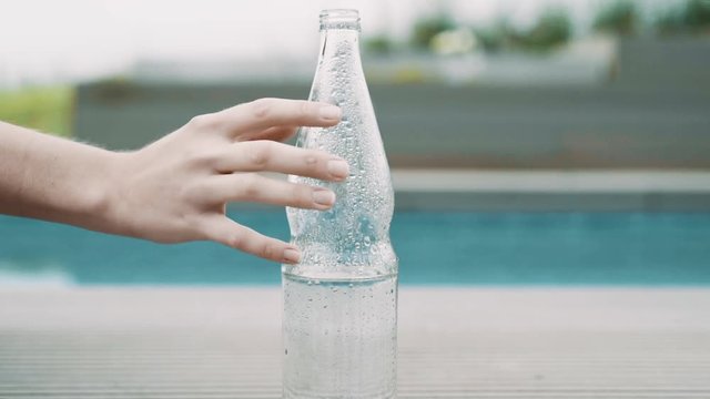Hand streift &uuml;ber Wasserflasche