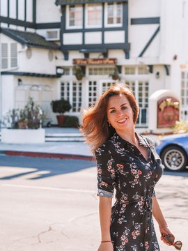 Portrait of a brunette girl with long hair and a black dress on the streets of Sunny Solvang, similar to Denmark