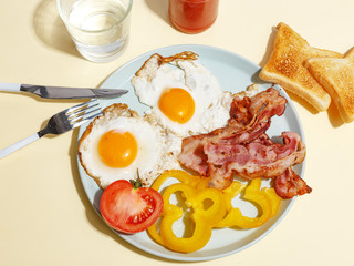 Simple breakfast. Fried egg with bacon, bell pepper and toast on a plate.