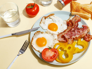 Simple breakfast. Fried egg with bacon, bell pepper and toast on a plate.