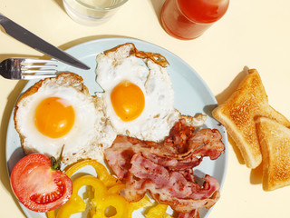 Simple breakfast. Fried egg with bacon, bell pepper and toast on a plate.