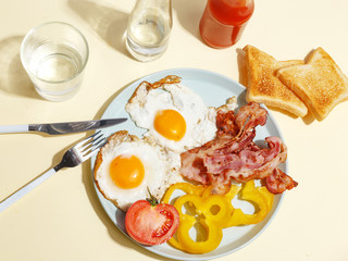 Simple breakfast. Fried egg with bacon, bell pepper and toast on a plate.