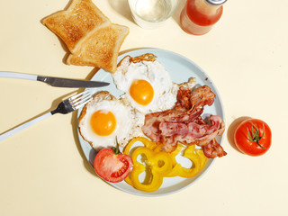 Simple breakfast. Fried egg with bacon, bell pepper and toast on a plate.