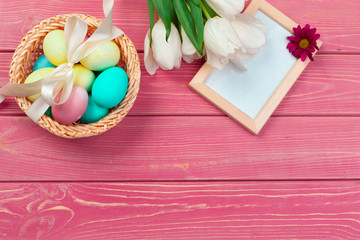 easter, holidays, tradition and object concept - close up of colored eggs and tulip flowers over wooden boards background