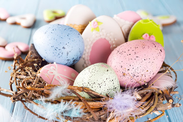 Naklejka na ściany i meble Colorful easter eggs cookies and easter eggs in wooden nest on blue wooden background, close up