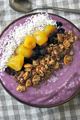 A colorful healthy breakfast of purple smoothies with granola and dried fruit.