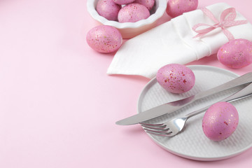 Easter. Pink Easter eggs and plate, knife and fork on a trendy pink background. Easter table setting. Happy easter. holidays.
