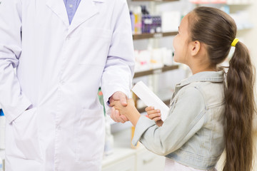 Fototapeta premium Pharmacist helping little girl at the drugstore
