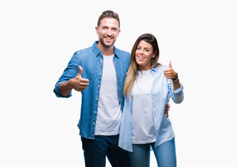 Young couple in love over isolated background doing happy thumbs up gesture with hand. Approving...