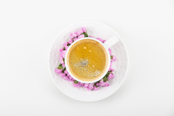White cup of coffee on a white table with pink flowers of dried flower. Minimalism. Top view, flat lay