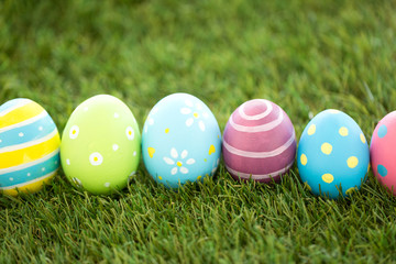 easter, holidays and tradition concept - row of colored eggs on artificial grass