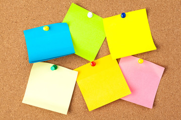 Cork board with several colorful blank notes with pins