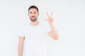 Fototapeta premium Young handsome man wearing casual white t-shirt over isolated background showing and pointing up with fingers number three while smiling confident and happy.