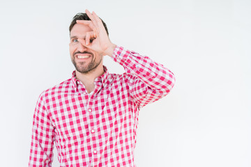 Fototapeta premium Young handsome man wearing shirt over isolated background doing ok gesture with hand smiling, eye looking through fingers with happy face.