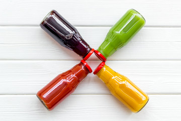 bottles with carrot, tomato, apple, cucumber, lemon, pomegranate juices on white wooden background top view copyspace