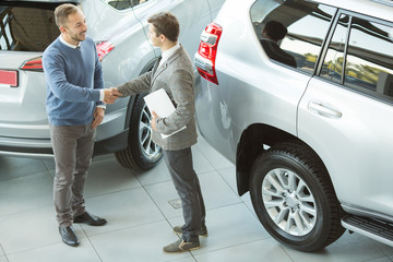 Male customer and car salesman at the dealership