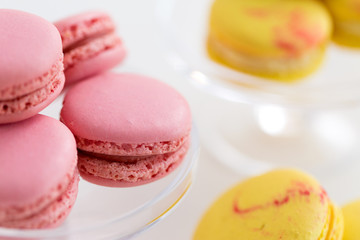 sweets, pastry and food concept - close up of pink and yellow macarons over white background