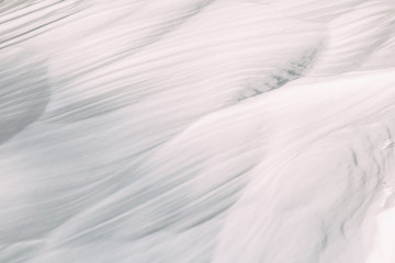 Obraz premium The wavy texture of fresh snow. White drifts and the sun.