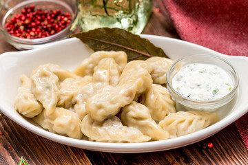 Dumplings in a white plate with sour cream