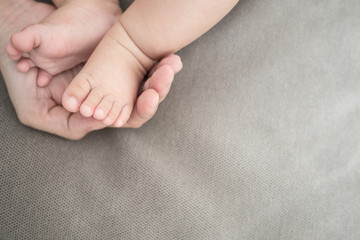 New born baby foot on grey fabric background