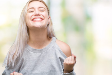 Young blonde woman over isolated background very happy and excited doing winner gesture with arms raised, smiling and screaming for success. Celebration concept.