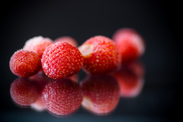 fresh frozen red ripe strawberries on a black