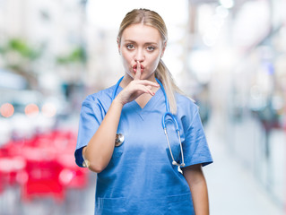 Young blonde surgeon doctor woman over isolated background asking to be quiet with finger on lips. Silence and secret concept.