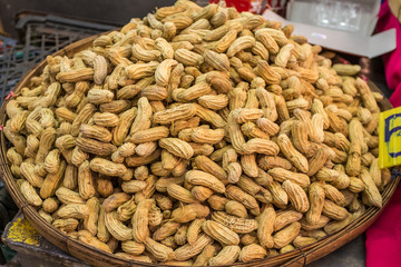 A large bowl of peanuts still in their husks at a street market in Thailand