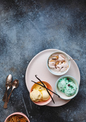 Bowls of various different scoops of ice cream on ceramics tray.  Top view, blank space, rustic background