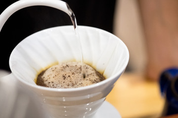 Alternative manual coffee brewing in ceramic dripper with paper filter.