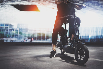 Trendy man hipster preparing for ride by electric scooter in the city. Innovative transport