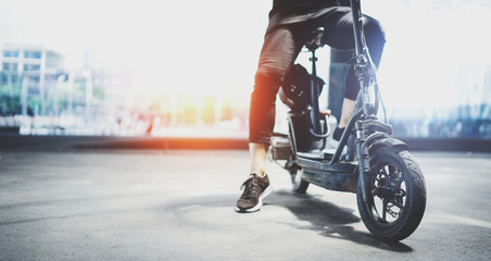 Electric urban transportation.Young man ready to ride his electric scooter bike in the center of a city. Wide. © SFIO CRACHO
