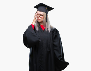 Young blonde woman wearing graduate uniform over isolated background smelling something stinky and disgusting, intolerable smell, holding breath with fingers on nose. Bad smells concept.