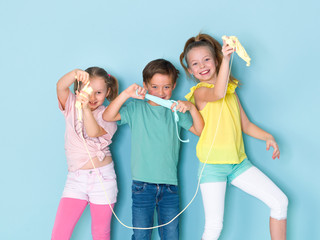 two beautiful and funny girls and one cool boy playing with a lot of slime in front of blue...