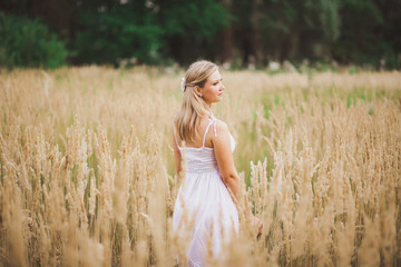 Portrait of pensive young beautiful girl standing outside in grassy meadow. Horizontal color photography.