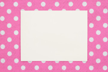 Blank beige greeting card on pink and white polka dot fabric