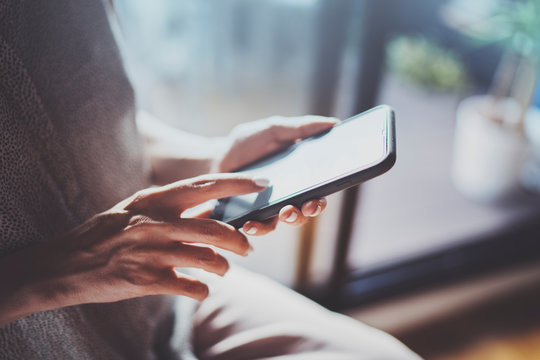 Female hands using mobile phone at sunny day in workplace.Horizontal. Blurred background