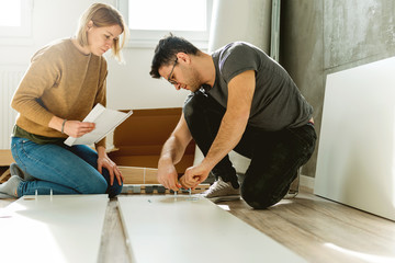 Fototapeta premium Couple assembling furniture in their new house 