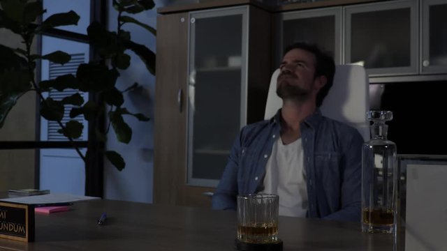 Frustrated Boss Working After Hours Takes a Drink of Whiskey.