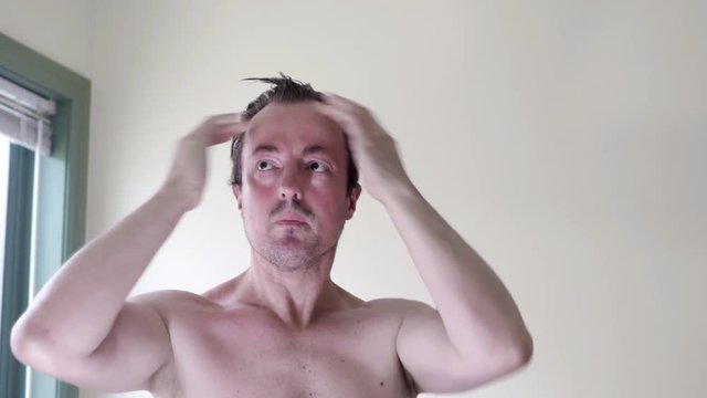 Man applying hair product to himself. Bare chested after having a shower. LOCKED DOWN SHOT.