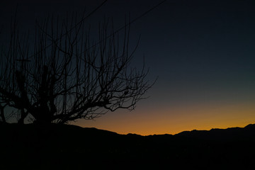 The orange glow of a sunset behind a distant mountain range