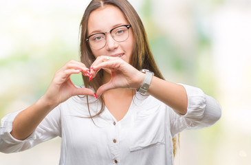 Young caucasian beautiful business woman wearing glasses over isolated background smiling in love showing heart symbol and shape with hands. Romantic concept.