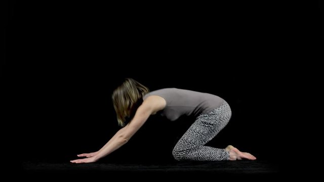 Full body side view of a woman demonstrating various yoga poses including the cat and cow pose isolated on a black studio background