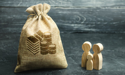 Miniature wooden family figurines stand near a money bag. The concept of savings. Budget planning....