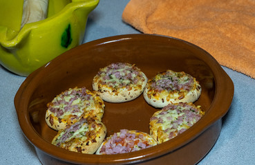 SMALL PIZZAS IN A ROLLED PLATE IN A KITCHEN TABLE