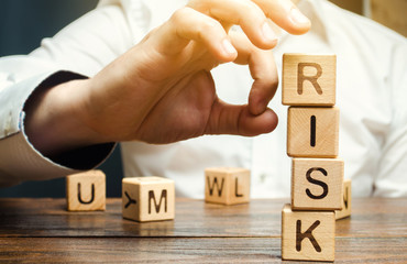 Hand removes blocks with the word Risk. The concept of reducing possible risks. Insurance,...