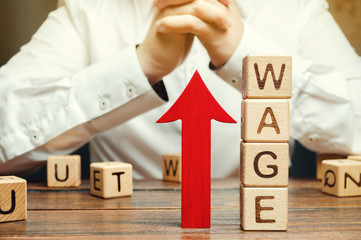Red arrow up near wooden blocks with the word Wage and a businessman. Salary increase concept....