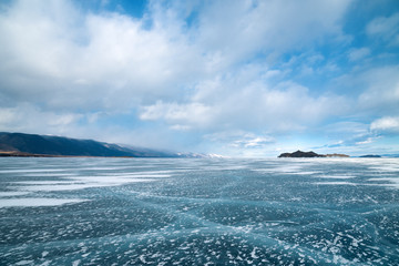Beautiful transparent ice with cracks of Lake Baikal in March. Siberia, Russia. Coast, islands.